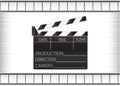 Black movie clapperboard and cine-film on gray background Royalty Free Stock Photo